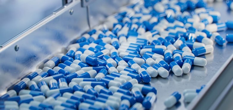 Blue and white pill capsules on a manufacturing line