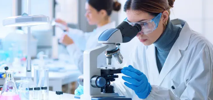 Scientist examining samples under a microscope in a lab